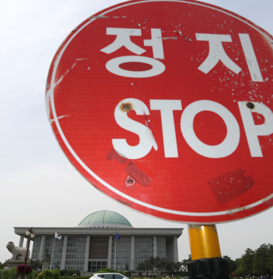 아직도 '올스톱' 여야 대립으로 파행이 장기화하고 있는 26일 오후 국회 정문에 차량을 통제하는 정지 표지판과 국회 본청이 대비되고 있다.   연합뉴스